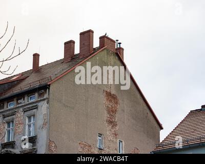 Kaputtes Mietshaus außerhalb eines Apartmenthauses. Gips löst sich von der Ziegelwand ab. Die Fassade ist in einem schlechten Zustand und muss renoviert werden. Stockfoto