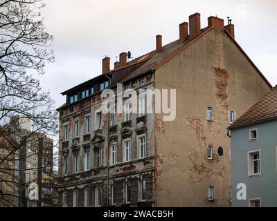 Heruntergekommenes Appartementgebäude in einem Wohnviertel. Die Fassade ist gebrochen und beschädigt, Risse im Putz und die rohe Ziegelwand ist sichtbar. Stockfoto