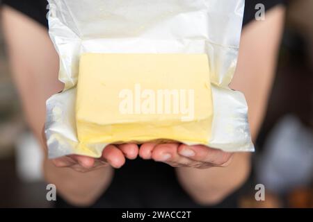 Eine Hand hält Butter in einer Nahaufnahme. Herstellung von Sandwiches mit Butter. Stockfoto