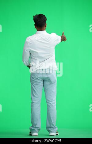 Ein Mann in einem weißen Hemd, auf grünem Hintergrund, in voller Höhe, zeigt einen Daumen nach oben, Rückansicht Stockfoto