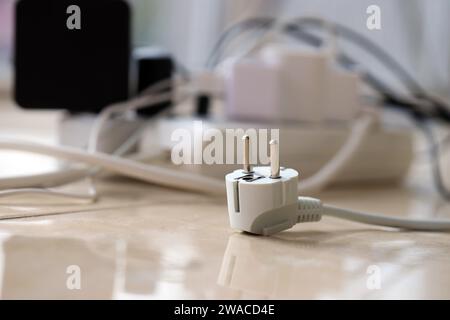 Überlastete Stromversorgungsplatinen. Steckdosenleisten mit verschiedenen Steckern auf weißem Boden. Konzept der Gefahr Gefahr Überlaststrom elektrisch Stockfoto