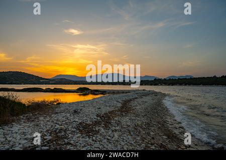 Sonnenuntergang über den Hügeln auf Lefkada von der Insel Meganisi im griechischen Ionischen Meer. Stockfoto