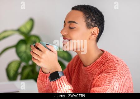 Zufriedene junge Frau mit einem ruhigen Ausdruck, die ihren Kaffee genießt Stockfoto
