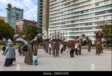 Eine Gruppe von Besuchern interagiert mit der Skulptur A-Labing Lachy des chinesischen Bildhauers Yue Minjun aus dem Jahr 2009. Morton Park, English Bay, Vancouver, Kanada. Stockfoto