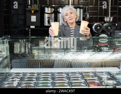 Lächelnde Senior Verkäuferin, die erfrischenden taiwanesischen boba-Tee anbietet Stockfoto