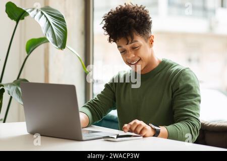 Ein glücklicher Schwarzer der Millennials benutzt Gadgets im Café Stockfoto