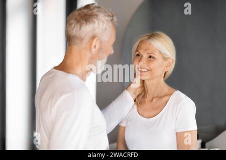 Romantisches älteres Ehepaar, das im Badezimmer einen zärtlichen Moment teilt Stockfoto