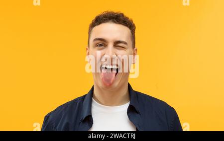 Porträt eines gutaussehenden europäischen Mannes, der Zunge zeigt, Glück ausdrückt Stockfoto