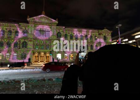 Helsinki, Finnland. Januar 2024. Eine Person fotografiert das beleuchtete Ateneum Art Museum während des Lichtfestivals Lux Helsinki in Helsinki, Finnland, am 3. Januar 2024. Lux Helsinki ist ein jährlich stattfindendes Festival der Lichtkunst, das Anfang Januar hier stattfindet. Quelle: Matti Matikainen/Xinhua/Alamy Live News Stockfoto