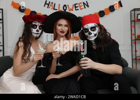 Gruppe von Menschen in gruseligen Kostümen mit Cocktails, die Halloween drinnen feiern Stockfoto