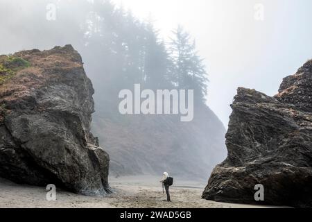 USA, Oregon, Brookings, Senior Frau, die zwischen Felsen am Strand steht Stockfoto