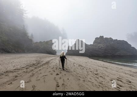 USA, Oregon, Brookings, Senior Woman Wander mit nordic Walking Stöcke am Strand Stockfoto
