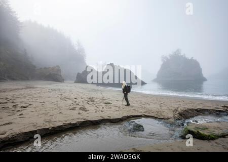 USA, Oregon, Brookings, Senior Frau am Strand in der Nähe des Baches Stockfoto