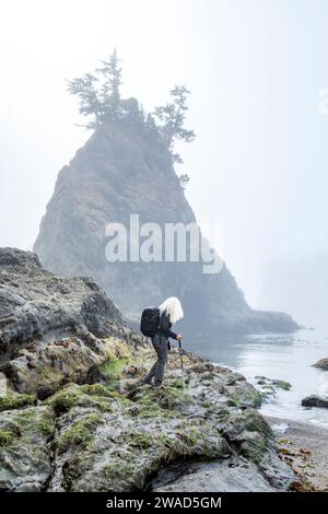 USA, Oregon, Brookings, Seniorin, die auf Felsen über dem Meer wandern Stockfoto
