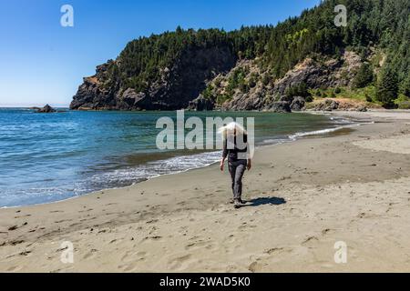 USA, Oregon, Brookings, Senior Woman, die am sonnigen Tag am Strand spazieren gehen Stockfoto