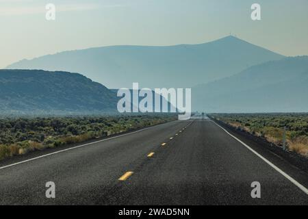 Leere Autobahn führt durch die Wüste mit Bergen im Hintergrund Stockfoto