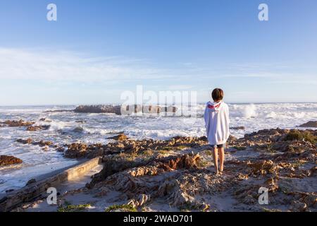 Südafrika, Hermanus, Junge (10-11), der auf Felsen am Kammabaai Beach steht Stockfoto