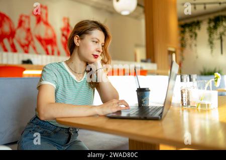 Ernsthafte Frau, die im Café an einem Laptop arbeitet Stockfoto