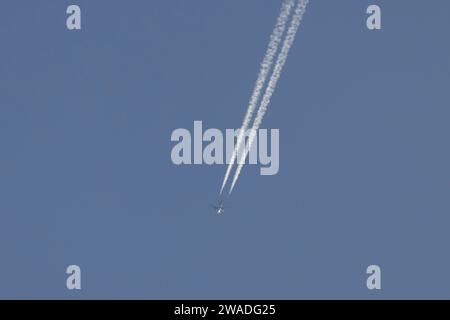 Jet-Flugzeuge fliegen über einen blauen Himmel und hinterlassen einen Kondensstreifen oder Dampfspur in der Atmosphäre hinter dem Flugzeug, England, Vereinigtes Königreich Stockfoto