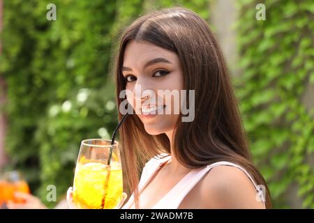 Schöne junge Frau mit einem Glas leckeren aperol Spritz Cocktail im Café, draußen Stockfoto