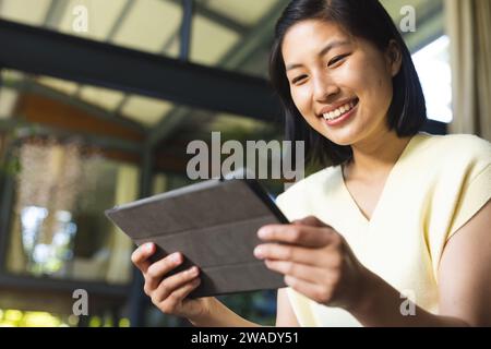Glückliche asiatische Frau mit kurzen Haaren, die zu Hause ein Tablet benutzt. Leben, Technologie und Lebensstil, unverändert. Stockfoto