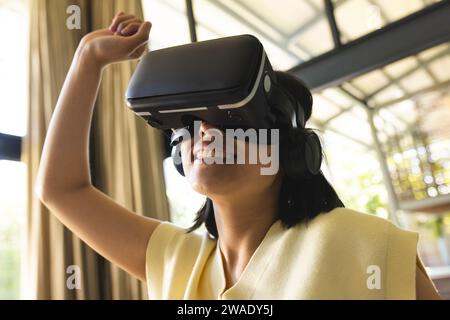 Glückliche asiatische Frau, die zu Hause das vr-Headset spielt und verwendet. Leben, Technologie und Lebensstil, unverändert. Stockfoto