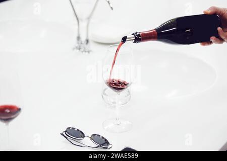 Nahaufnahme eines Sommeliers, der Rotwein in Weinglas gießt. Schulung und Weinprobe. Stockfoto