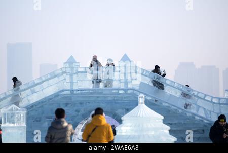 (240104) -- HARBIN, 4. Januar 2024 (Xinhua) -- Touristen haben Spaß in Harbin Ice-Snow World in Harbin, nordöstlicher chinesischer Provinz Heilongjiang, 3. Januar 2024. Die Provinz Heilongjiang verfügt über reichlich Eis- und Schneeressourcen, was sie zu einem beliebten Reiseziel für Wintertourismus in China macht und zahlreiche Touristen aus dem in- und Ausland während der Neujahrsferien anzieht. Die „ICE City“ Harbin, die Hauptstadt der Provinz Heilongjiang, begrüßte fast 3,05 Millionen Besucher und erzielte während des Feiertags, der Montag endete, 5,91 Milliarden Yuan (etwa 832,39 Millionen US-Dollar) an Tourismuseinnahmen. Um Mo Stockfoto