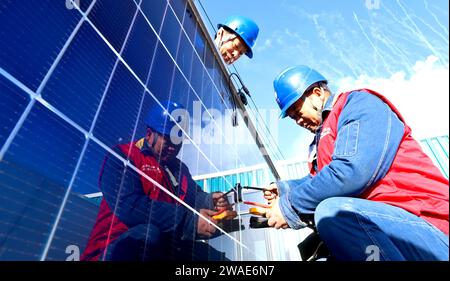 ZHANGYE, CHINA - 4. JANUAR 2024 - Power Workers testen und debuggen die Photovoltaik-Anlage am netzverbundenen Stromerzeugungsstandort einer Viehfarm Stockfoto