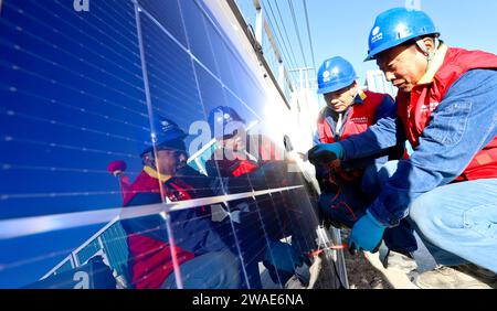 ZHANGYE, CHINA - 4. JANUAR 2024 - Power Workers testen und debuggen die Photovoltaik-Anlage am netzverbundenen Stromerzeugungsstandort einer Viehfarm Stockfoto