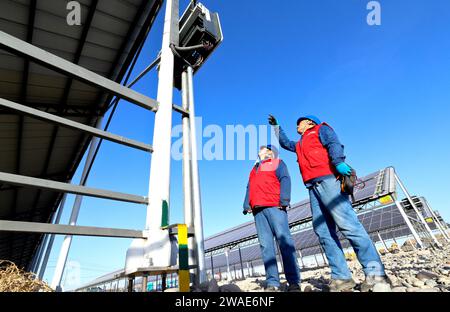 ZHANGYE, CHINA - 4. JANUAR 2024 - Stromversorger überprüfen Photovoltaik-Anlagen an der netzverbundenen Stromerzeugungsanlage des Viehbestands Stockfoto