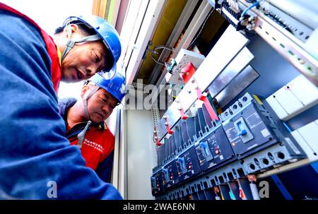 ZHANGYE, CHINA - 4. JANUAR 2024 - Power Workers debuggen Photovoltaik-Array-Übertragungsgeräte am netzverbundenen Stromerzeugungsstandort eines Live Stockfoto