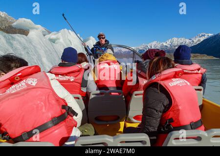 Ein Ausflugsboot auf dem Tasman Lake, einem Gletschersee im Mount Cook National Park, Neuseeland. Neben dem Boot befindet sich einer der Eisberge, die auf dem See schweben Stockfoto