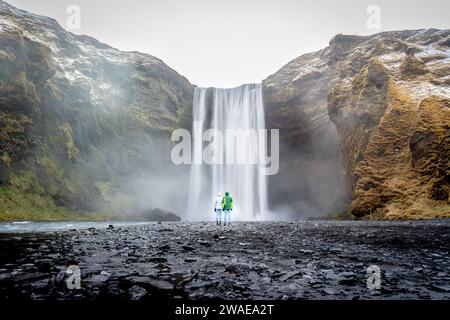 Ein Mann mittleren Alters staunt über einen mächtigen Wasserfall, umgeben von üppigem Grün Stockfoto