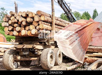 Holzträger mit großen, gesägten Stämmen am Holzlagerplatz und Stapel russischer Rubel in der Hand. Forstindustrie Stockfoto