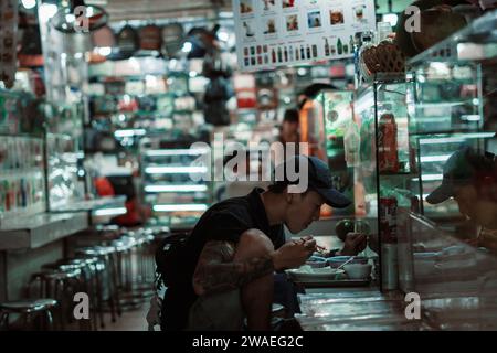 Ein Mann auf der Suche nach Produkten auf dem Straßenmarkt in Ho Chi Minh, Vietnam Stockfoto