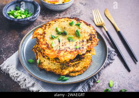 Hausgemachte Kartoffelrösti oder Kartoffelpfannkuchen mit Kohl-Salat und grünen Zwiebeln Stockfoto