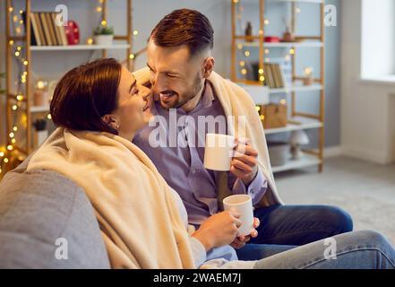 Glückliches Paar, das heiße Schokolade zu Hause genießt Stockfoto
