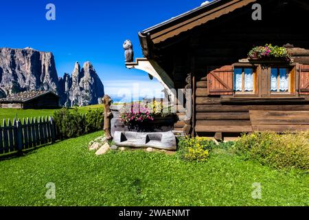 Ein Holzhaus auf einem Hügel auf der Seiser Alm, Seiser Alm, Schlern, in der Ferne. Stockfoto