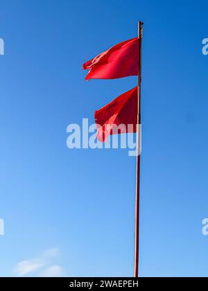 Zwei rote Fahnen am Strand warnen vor einem Sturm auf See Stockfoto