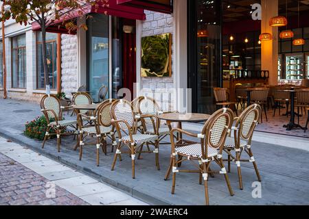 Straßenblick auf eine Kaffeeterrasse mit Tischen und Stühlen. Kostenloser Kaffeetisch. Leerer Kaffee im Freien und Restaurantterrasse an einem Sommertag in Europa Stockfoto