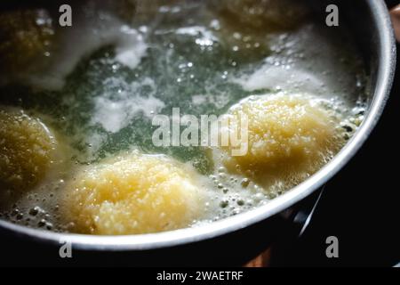 Bayern, Deutschland - 25. Dezember 2023: Kartoffelklöße in einem Kochtopf mit kochendem Wasser *** Kartoffelklöße in einem Kochtopf mit kochendem Wasser Stockfoto