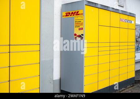 Innovative Paketlogistik - Nutzung der DHL Packstation 04.01.2024, Bad Camberg: Symbolfoto, Illustrationsbild, Symbolbild, Illustrationsfoto das Bild zeigt eine Frau im Anschnitt, die mit ihrem Smartphone über den Touchscreen einer DHL Paketstation interagiert, um ein Paket einzureichen. Sie ist konzentriert auf die digitale Schnittstelle fokussiert, während Ihre Hand das Mobiltelefon hält und die entsprechenden Eingaben auf dem Bildschirm der Paketstation tätigt um das Paket einlegen. Die Packstation, ein Paketautomatensystem von DHL, bietet seit 2001 in über 12,500 Standorten deutschlandwe Stockfoto