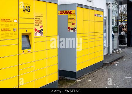 Innovative Paketlogistik - Nutzung der DHL Packstation 04.01.2024, Bad Camberg: Symbolfoto, Illustrationsbild, Symbolbild, Illustrationsfoto das Bild zeigt eine Frau im Anschnitt, die mit ihrem Smartphone über den Touchscreen einer DHL Paketstation interagiert, um ein Paket einzureichen. Sie ist konzentriert auf die digitale Schnittstelle fokussiert, während Ihre Hand das Mobiltelefon hält und die entsprechenden Eingaben auf dem Bildschirm der Paketstation tätigt um das Paket einlegen. Die Packstation, ein Paketautomatensystem von DHL, bietet seit 2001 in über 12,500 Standorten deutschlandwe Stockfoto