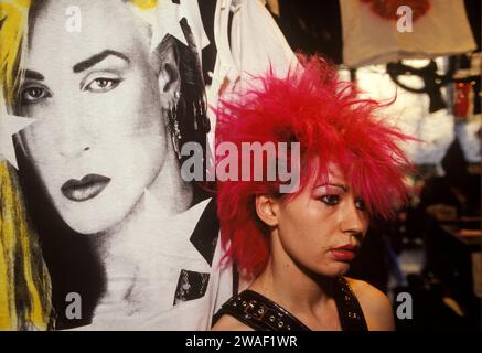 Punk-Teenager-Mädchen kaufen Assistent in Boy in 153 Kings Road, Chelsea Boutique, 1980er Jahre Stachelig leuchtend rot gekämmtes Punkhaar und traurig aussehend, unter dem Poster von Peter Robinson, einem britischen jamaikanischen Popsänger; besser bekannt als Marilyn, der an der Spitze der New Romantic Movement stand. Chelsea, London, England 1983 HOMER SYKES Stockfoto