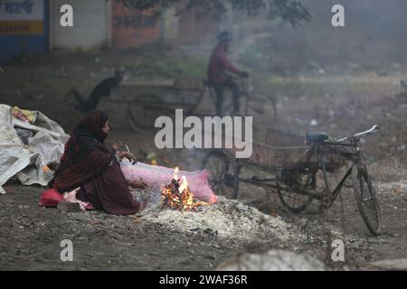 (240104) -- AMRITSAR, 4. Januar 2024 (Xinhua) -- Eine Frau sitzt am Feuer, um sich warm zu halten im Amritsar District im nördlichen Punjab Bundesstaat Indien, 4. Januar 2024. (Fil/Xinhua) Stockfoto
