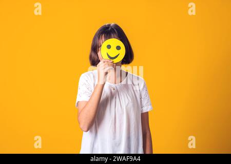 Das Mädchen hält glückliche Emoticons im Gesicht. Psychische Gesundheit, Psychologie und kindliches Gefühlskonzept Stockfoto