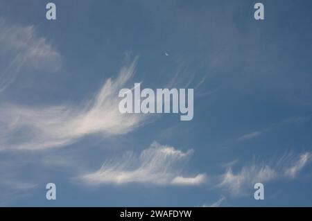 Hohe dünne Wolken (Cirrus und Cirrostratus) und Halbmond Stockfoto