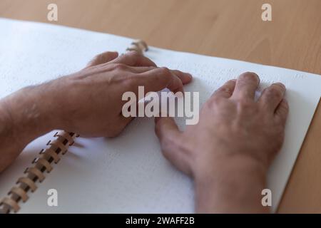 Blinde oder sehbehinderte Person, die ein Buch liest, das mit brailleschrift gedruckt ist. Stockfoto
