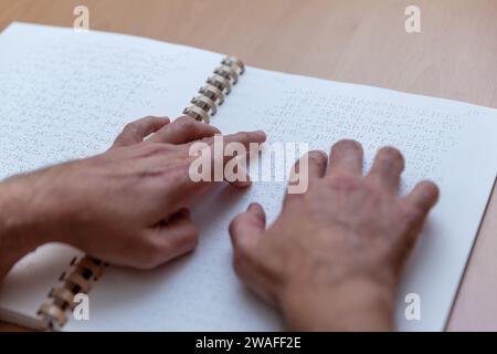 Blinde oder sehbehinderte Person, die ein Buch liest, das mit brailleschrift gedruckt ist. Stockfoto